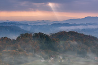 Sun breaks the clouds above Gresne Gorice hills in autumn fog, Zagorje, Croatia